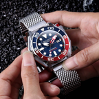 Person holding a silver watch with a blue and red face
